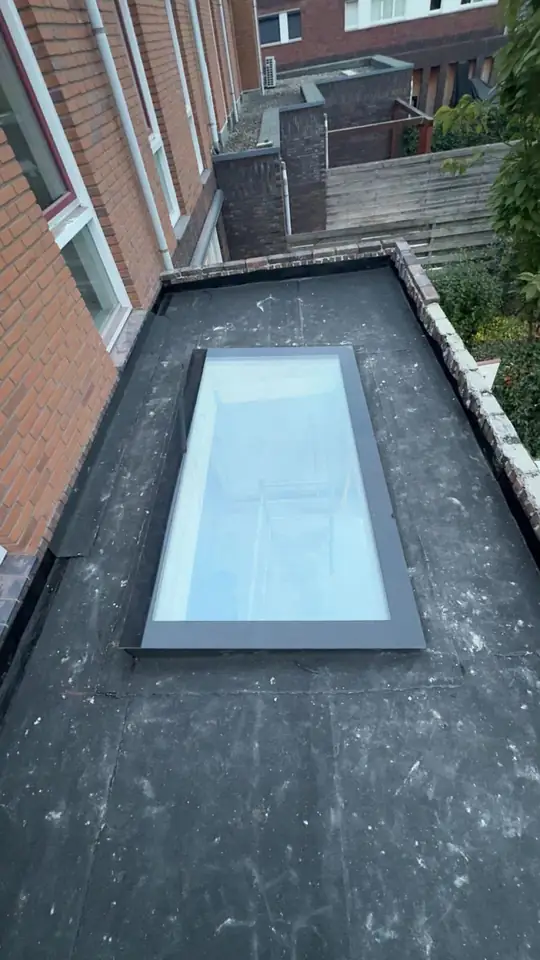 Na: afgewerkt plat dak met bitumen dakbedekking en een grote glazen lichtkoepel