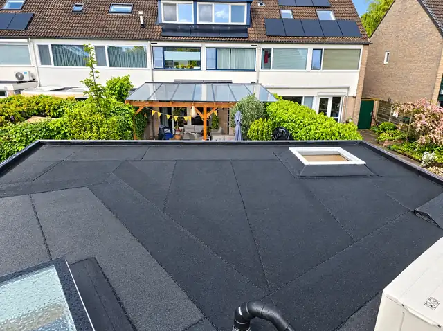 Plat dak met dakraam en nieuwe bitumen dakbedekking achter een rijwoning